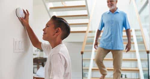 Image: a child adjusting a thermostat.