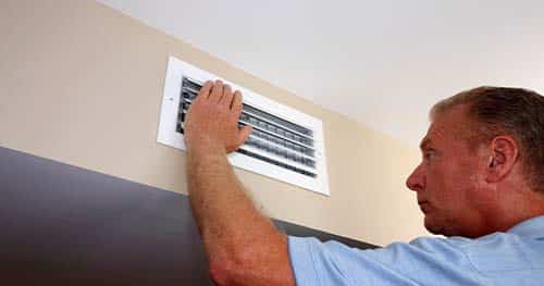 Image: a homeowner checks his vents to see why they're not working.