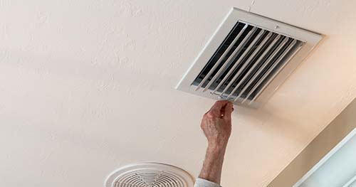 Image: a person adjusting the vents in their home.