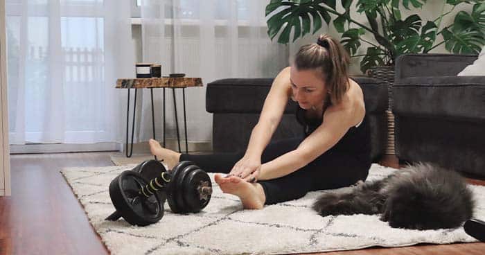 Image: a woman working out with her cat in a home gym.
