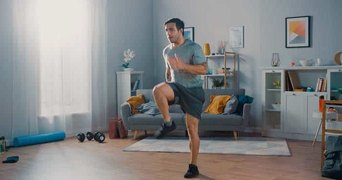 Image: a man working out in his own home gym with good ventilation.