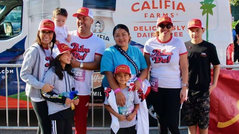 Members of the Adeedo team, dressed in branded shirts and hats, smile together outside beside a Califia Farms service van.