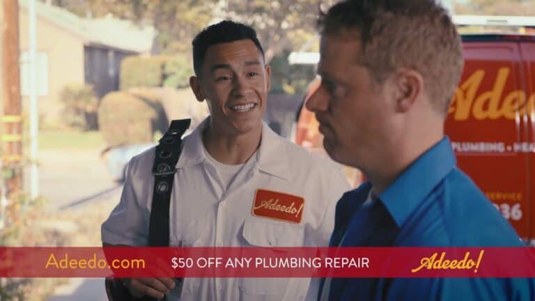 An Adeedo! plumber greets a customer outdoors by a red service van. A banner highlights $50 off plumbing repair services.